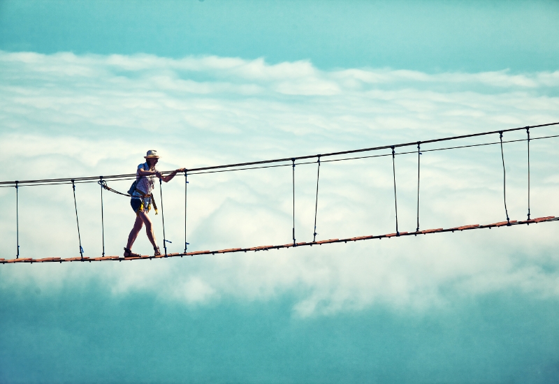 Woman crossing a rope bridge.